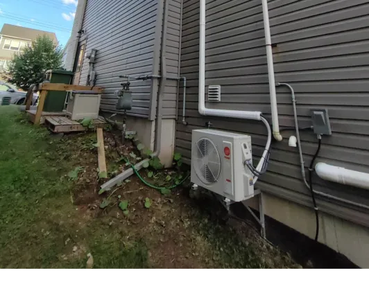 Ductless mini-split condenser installed beside a home with the lineset run to the wall