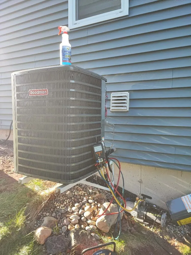 Residential air conditioning condenser installed beside blue vinyl siding